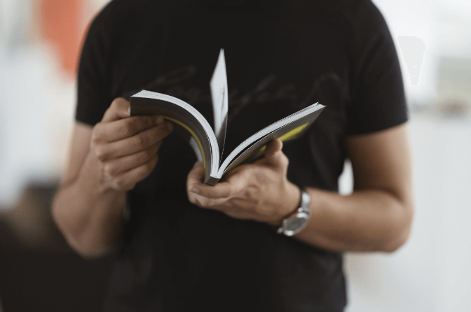 A man in a black shirt holds an open print-on-demand book.