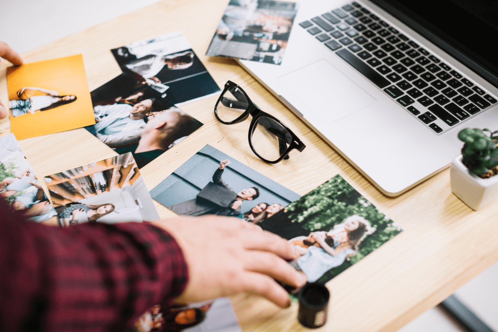 A man stands over a desk covered in printed photos.