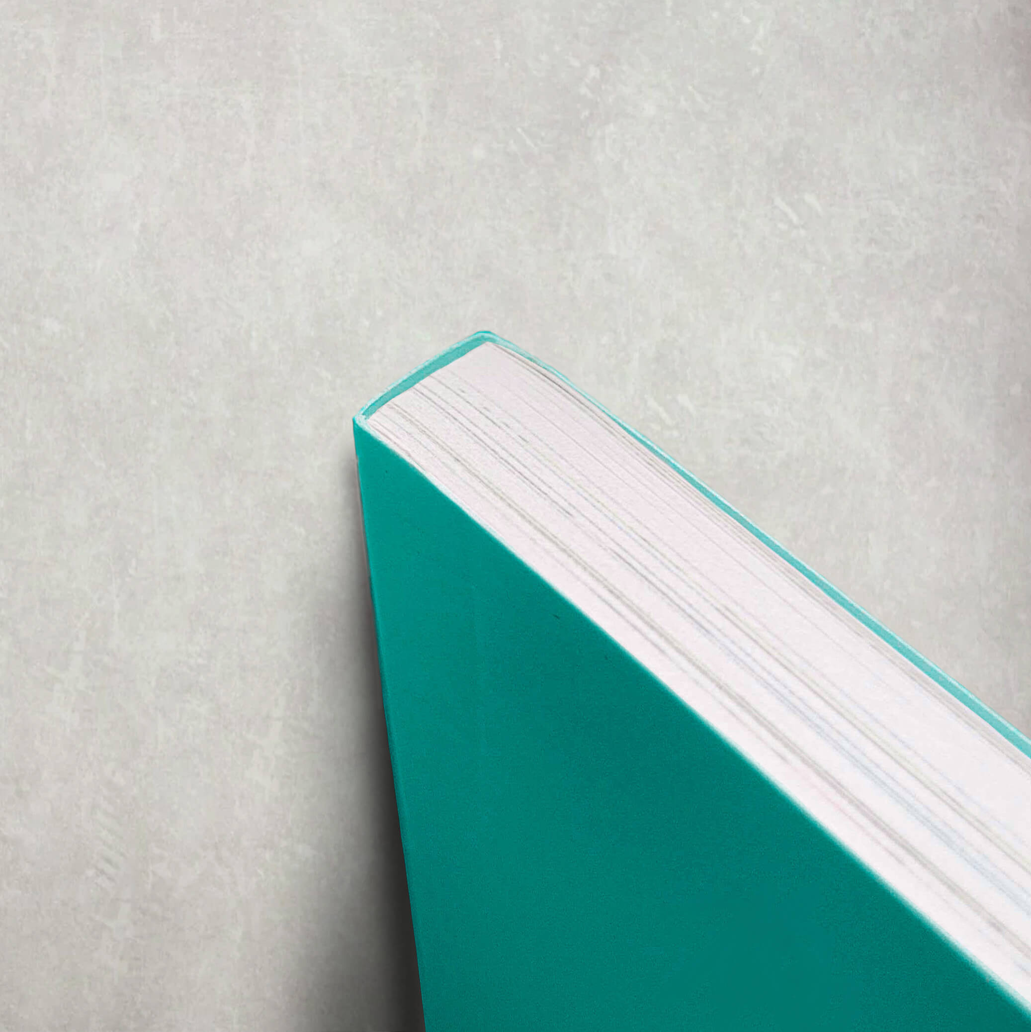 A close-up of a paperback book with a green cover resting on a white surface, showcasing its perfect binding.